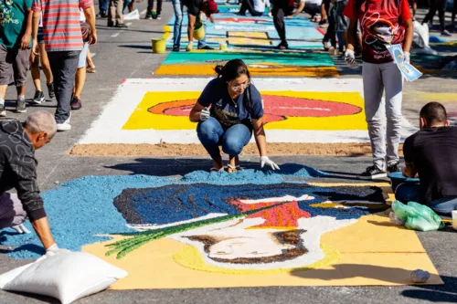 Os fiéis enfeitam as ruas com tapetes de flores, serragem e outros materiais, criando um caminho colorido e reverente para a passagem do Santíssimo