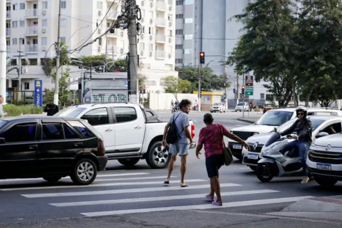 Pedestres se arrincam entre os carros para atravessar