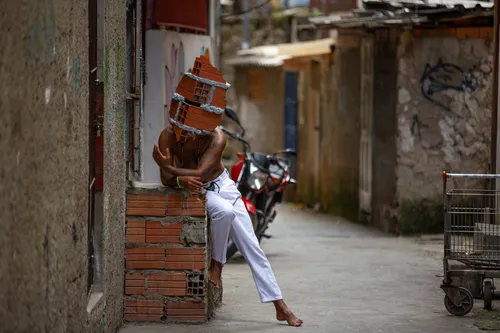 Nas obras, pessoas em favelas usam máscaras em formato de casa