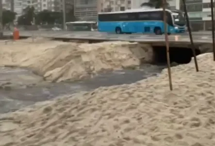 A água suja e preta deixa um rastro na areia e desemboca no mar