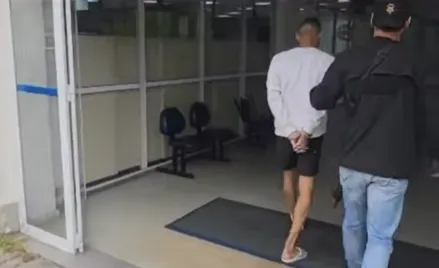 O preso (casaco branco) é levado para a Cidade da Polícia