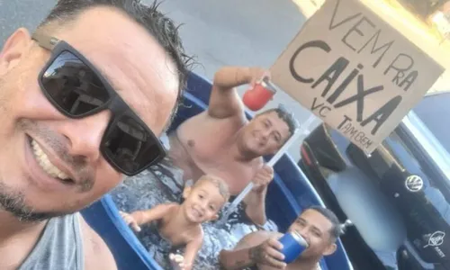 Família segurando o cartaz com o famoso bordão do banco Caixa enquanto se refresca na "piscina"