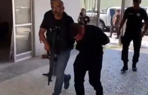 Um dos presos é conduzido por policiais da DHNSG