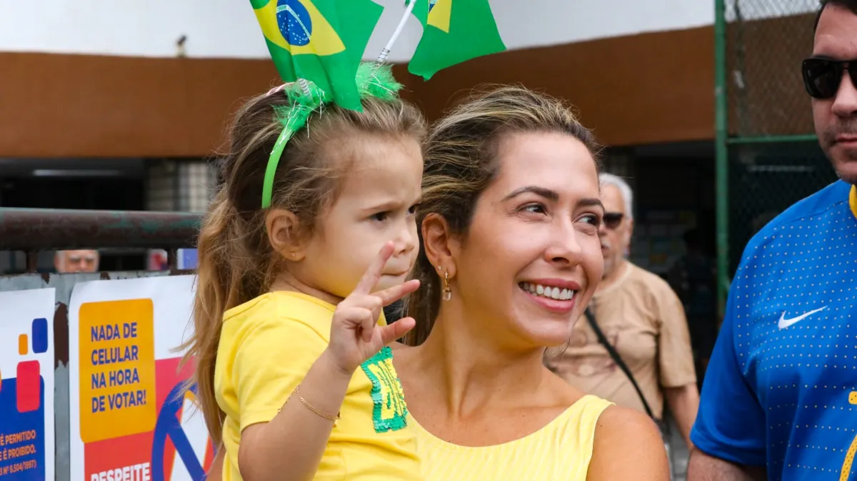 Trajada de verde e amarelo, a estudante fez questão de levar a filha ao local de votação