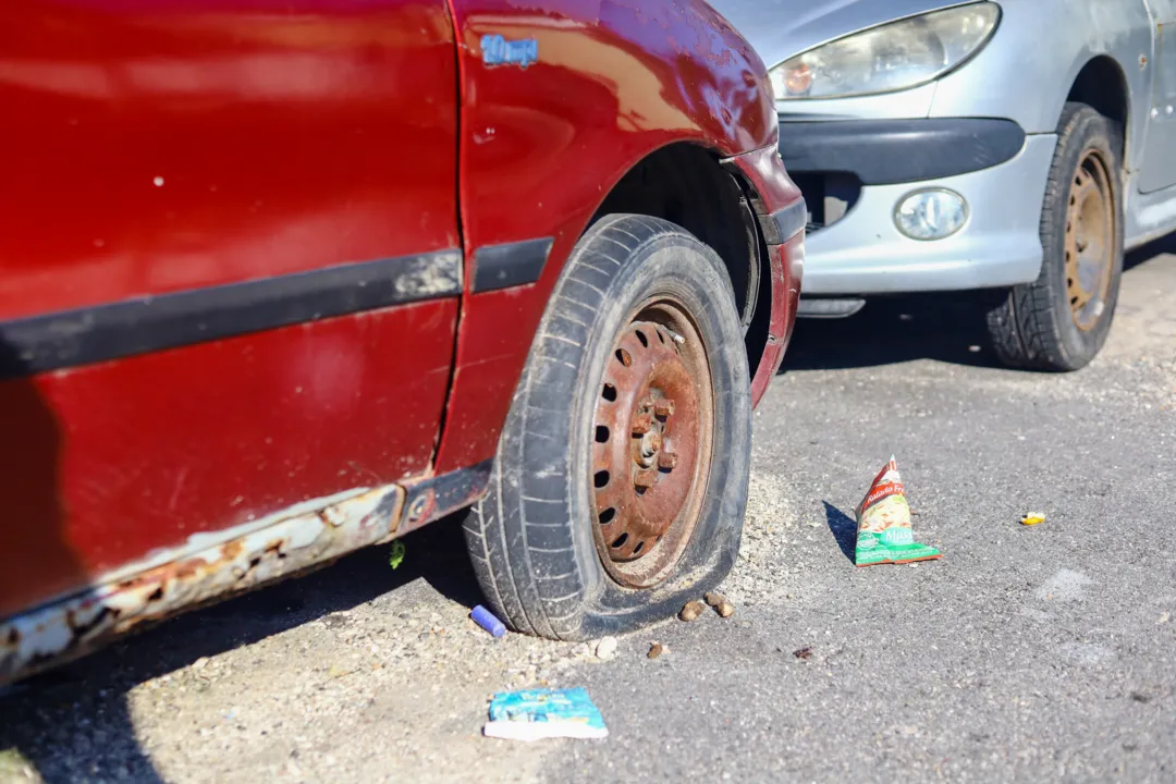 Próximo ao carro, há lixo e sujeira 