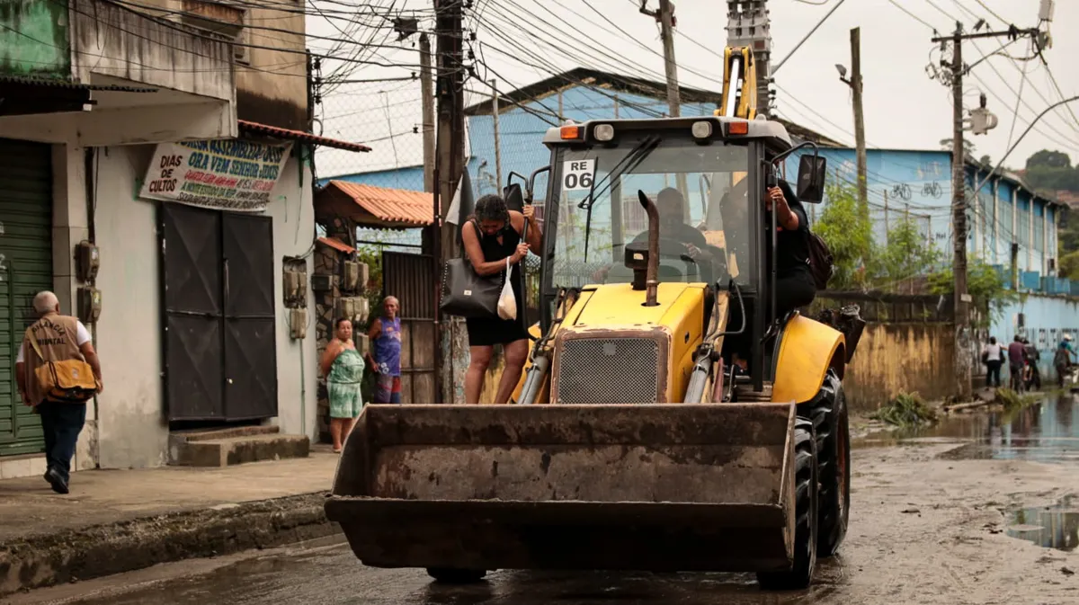 Moradora sendo carregada por retroescavadeira em São Gonçalo