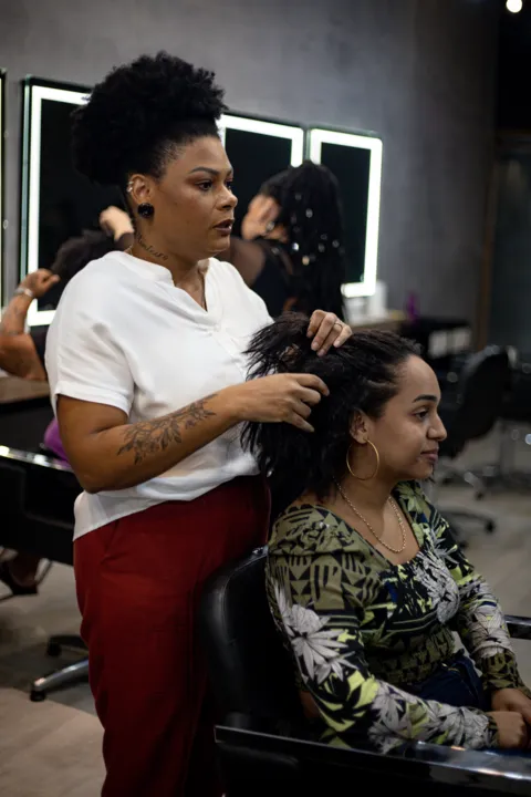 Lohane (sentada) antes da transição, com o cabelo com as pontas alisadas 