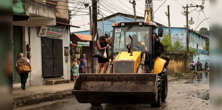 Moradora sendo carregada por retroescavadeira em São Gonçalo