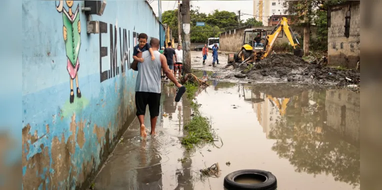 Morador carrega filho no colo para passar no local