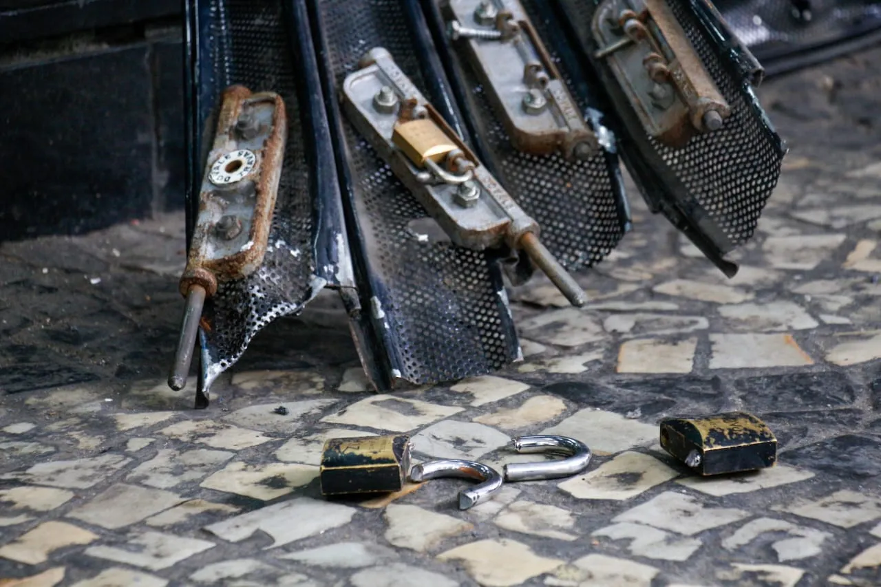 Cadeados e parte da porta eletrônica no chão da rua onde o crime aconteceu