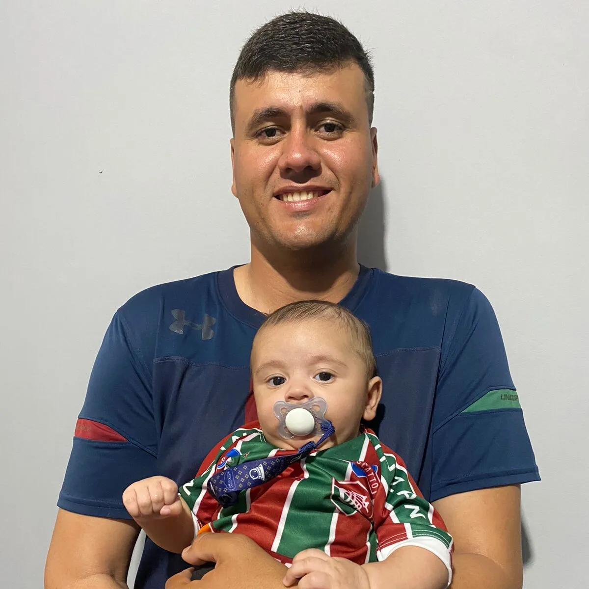 Gabriel segura o filho João Gabriel, de apenas quatro meses, que já herda o amor pelo Fluminense