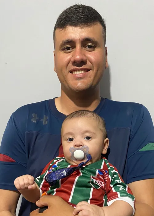 Gabriel segura o filho João Gabriel, de apenas quatro meses, que já herda o amor pelo Fluminense
