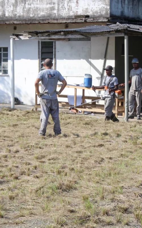 Homens trabalham na capina do terreno onde será construído o terminal