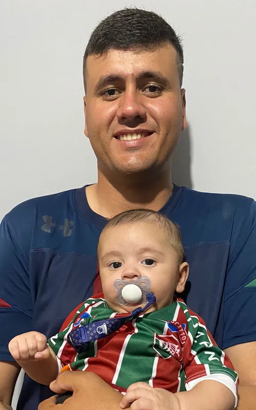 Gabriel segura o filho João Gabriel, de apenas quatro meses, que já herda o amor pelo Fluminense