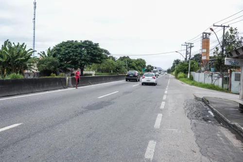 Pedestres esperam para atravessar entre concretos que dividem as pistas.