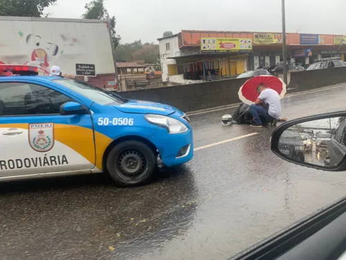 Um homem prestava apoio à vítima usando um guarda-chuva