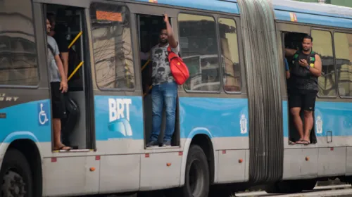 Passageiros em pé na porta de um ônibus do BRT: descaso