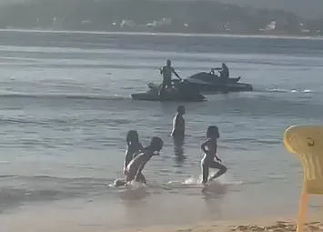 Crianças brincam na água no momento em que as motos aquáticas se aproximam