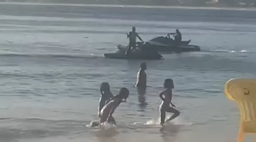 Crianças brincam na água no momento em que as motos aquáticas se aproximam